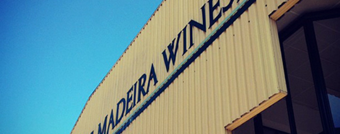 Beiges Industriegebäude mit Glasfenstern und blauem Himmel im Hintergrund.