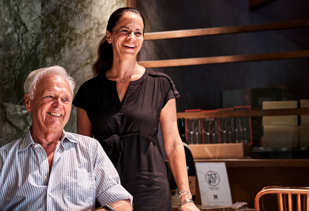 Zwei lachende Personen in einem stilvollen, modern eingerichteten Raum mit Holzmöbeln.