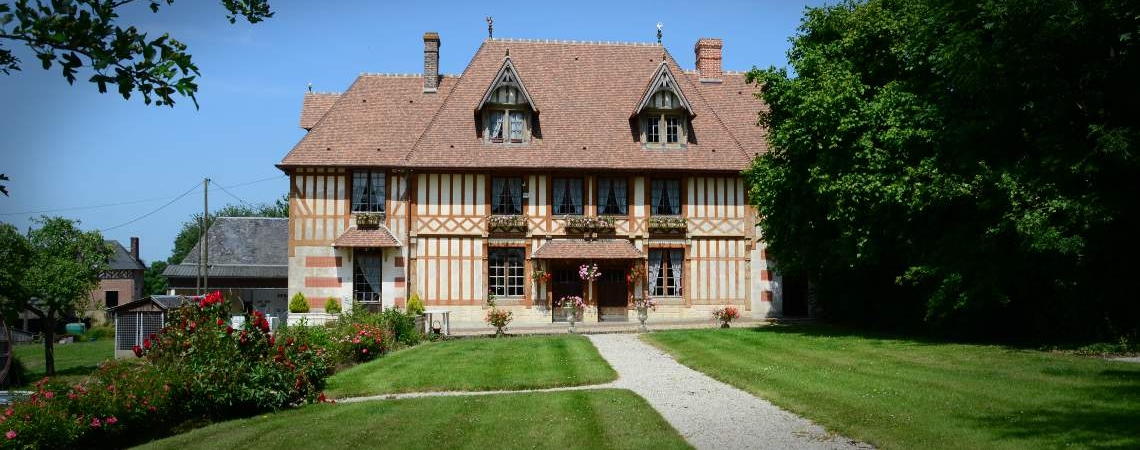 Fachwerkhaus mit symmetrischen Fenstern, rotem Ziegeldach und gepflegtem Garten.
