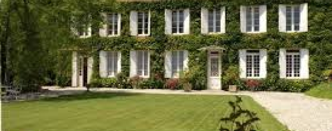 Historische Villa mit Efeu bewachsen, umgeben von gepflegtem Rasen und Kieswegen.