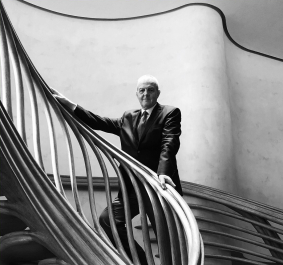 Eleganter Mann in Anzug auf kurviger, moderner Holztreppe; monochromes Design.