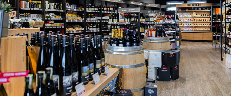 Moderner Weinladen mit stilvollen Holzregalen und Fassdekorationen.