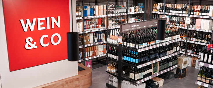 Moderner Weinladen mit Regalen voller Wein- und Spirituosenflaschen.