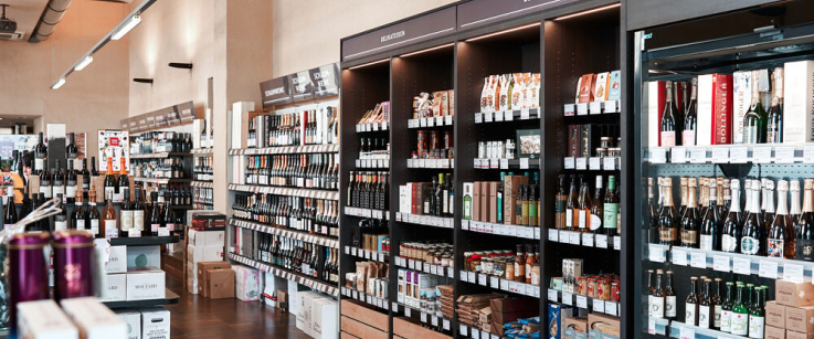 Moderner Feinkostladen mit Regalen voller Weinflaschen und Gourmetprodukten.