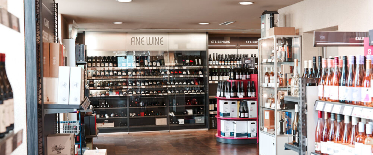 Moderner Weinladen mit stilvoll arrangierten Flaschenregalen und Holzboden.