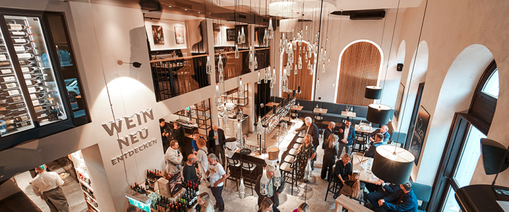 Elegante Weinbar mit hohen Decken, stilvollen Lampen und geselligem Ambiente.