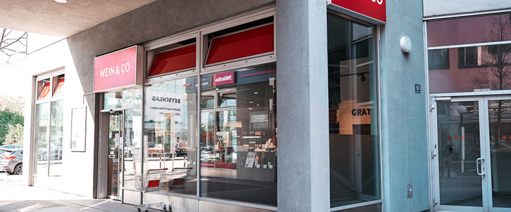 Eckgeschäft mit großen Fenstern und rotem Firmenschild.