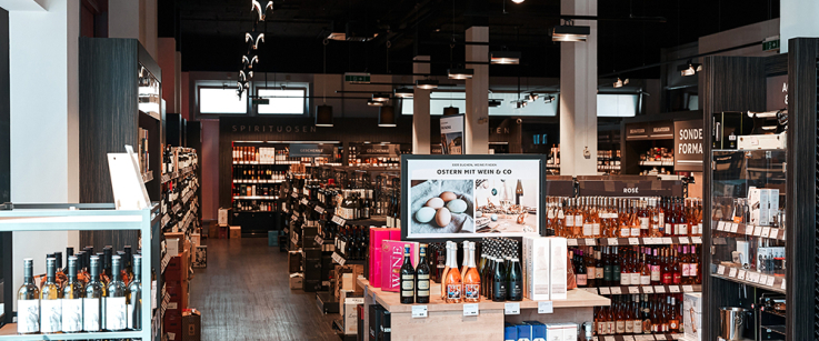 Moderner Weinladen mit Regalreihen voller Weinflaschen und rustikalem Holzboden.