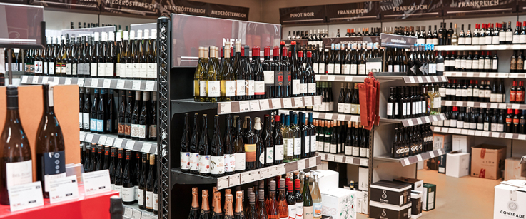 Regalreihen voller Weinflaschen in einem gut beleuchteten Laden.