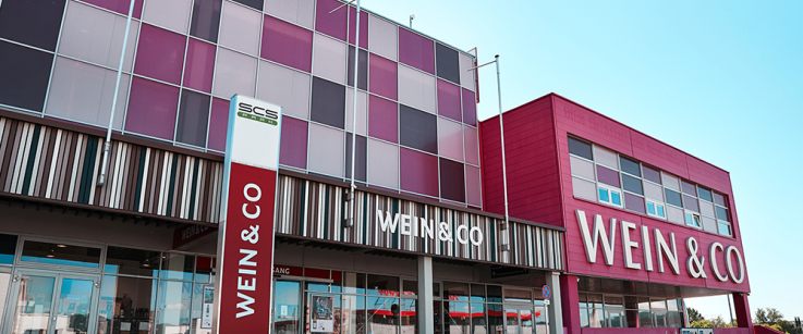 Modernes Gebäude mit bunten Glasfronten und auffälligem roten Schriftzug.