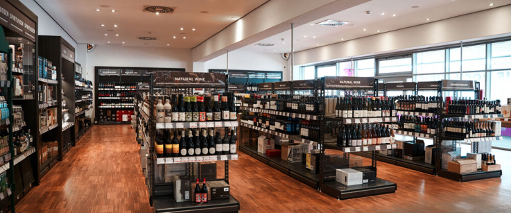 Heller Laden mit Regalen voller Weinflaschen in modernem Ambiente.