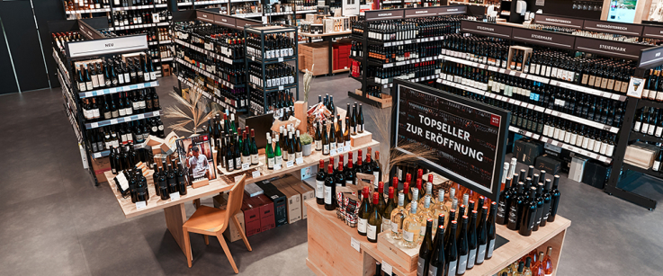 Moderner Weinladen mit gut sortierten Regalen und einem ansprechenden Präsentationstisch.
