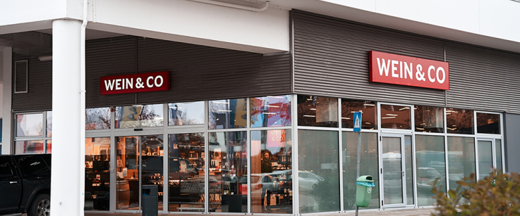 Moderne Ladenfassade mit großen Glasfenstern und rotem Firmenschild.