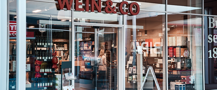 Weinladen mit Glasfassade und einladendem Eingang, elegant beleuchtet.