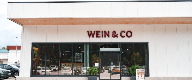 Modernes Geschäft mit großen Glasfenstern und Parkplatz, schlichtes Design.