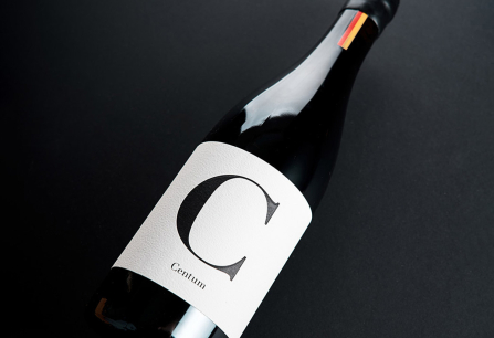 Schwarze Weinflasche mit elegantem, minimalistischen weißen Etikett auf dunklem Hintergrund.