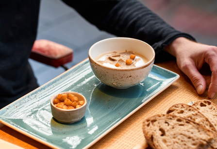 Keramikschale mit Suppe und kleinen Croutons auf stilvollem, türkisem Teller.
