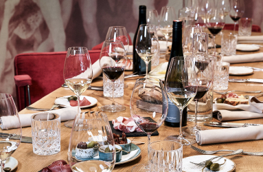 Eleganter gedeckter Tisch mit Weingläsern, roten Stühlen und feinem Geschirr.