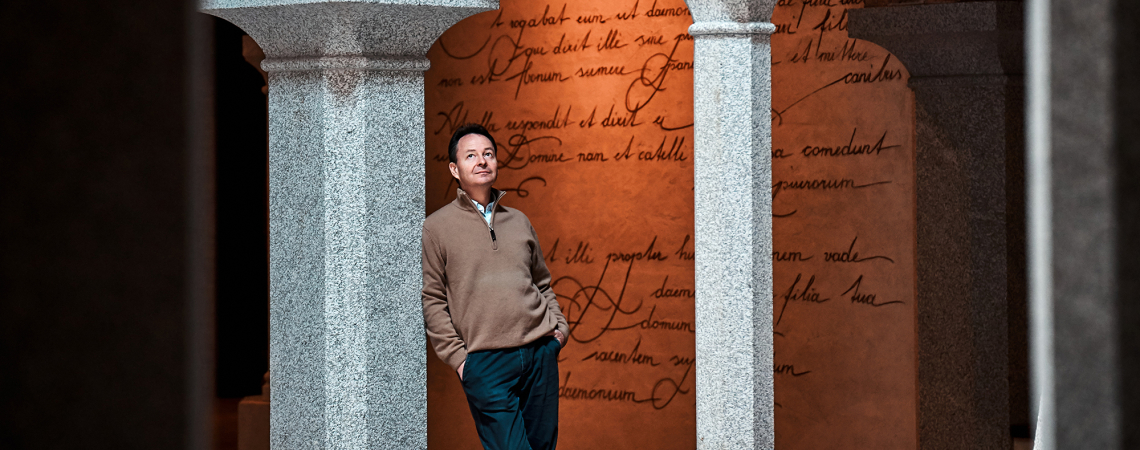 Person in historischem Gebäudegang mit Ziegelbögen und Steinsäulen.