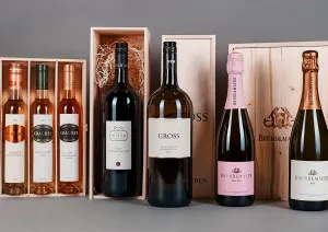 Weinflaschen und Sektflaschen in Holzkisten auf grauem Hintergrund.