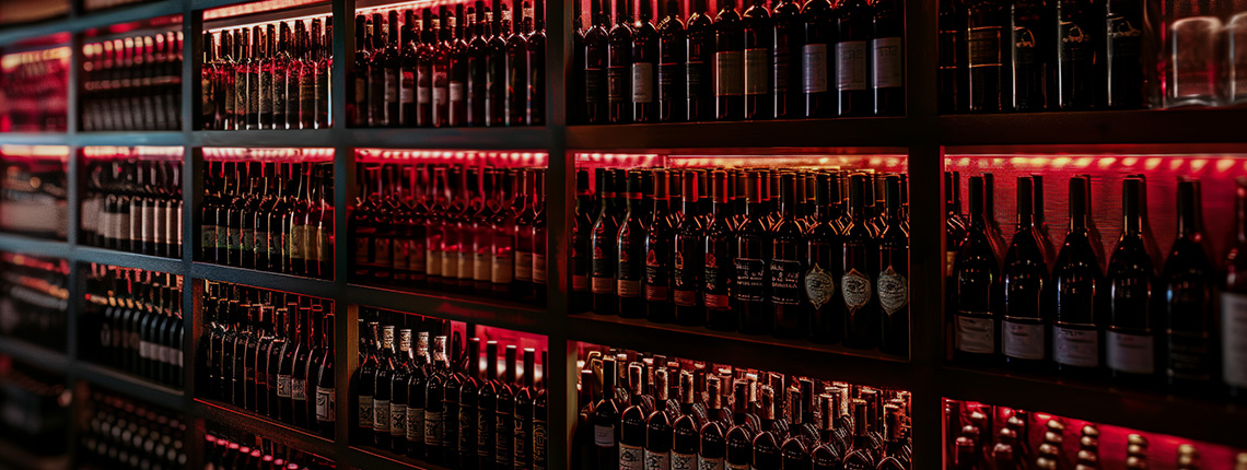 Regale voller Weinflaschen, stimmungsvoll beleuchtet mit warmem, rotem Licht.